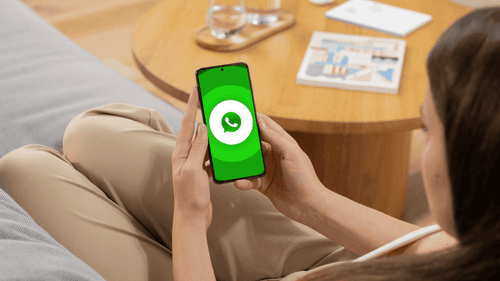 Mujer con celular en la mano. Logo de WhatsApp.
